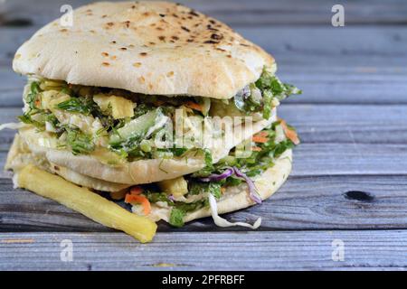 Flat Shami Syrian Bread gefüllt mit pommes Frites und grünem Salat, traditionelle ägyptische frittierte Kartoffeln Finger Sandwich umgeben von kühlen und knusprigen umgeben Stockfoto