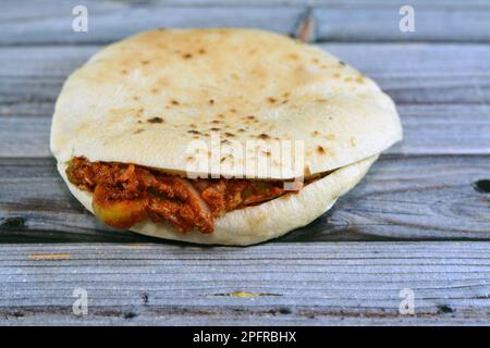 Alexandrianische würzige ägyptische zerdrückte Fava-Bohnen mit Paprika, Gewürzen, Öl und Tahini in flachem Shami-Brot, selektiver Fokus auf traditionellem Po Stockfoto