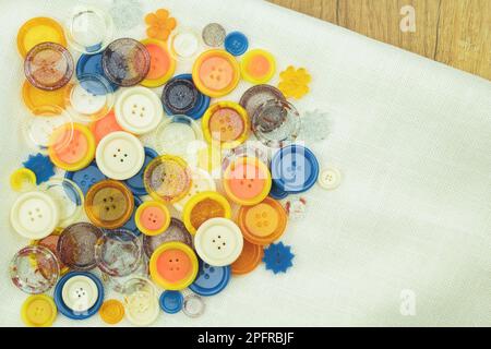 Viele Tasten in verschiedenen Farben und Größen. Farbige und helle Nähknöpfe auf dem Stoff. Draufsicht Nahaufnahme Stockfoto