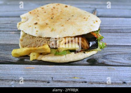 Mischung aus Kartoffeln, gebratenen Fingern, pürierten Fava-Bohnen, gebratener Aubergine, ägyptischem Falafel-grünen Burger, gekochten Eiern und Tahini gefüllt in einem Shami flatbre Stockfoto