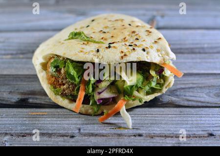 Gefülltes Falafel-Sandwich, ein sehr beliebtes und traditionelles ägyptisches Essen, ein Shami-syrisches Pita-Brot gefüllt mit knusprigen heißen Falafel-Bällen mit kühlem und Stockfoto