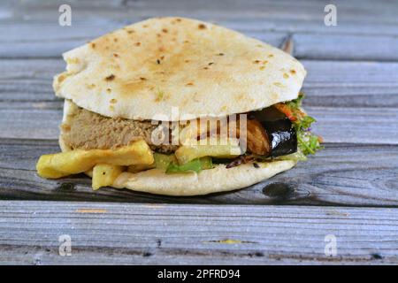 Mischung aus Kartoffeln, gebratenen Fingern, pürierten Fava-Bohnen, gebratener Aubergine, ägyptischem Falafel-grünen Burger, gekochten Eiern und Tahini gefüllt in einem Shami flatbre Stockfoto