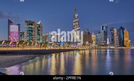 Die Skyline von Doha Qatar von der corniche Promenade in der Abenddämmerung zeigt die Wolkenkratzer der West Bay, die sich im arabischen Golf spiegeln Stockfoto
