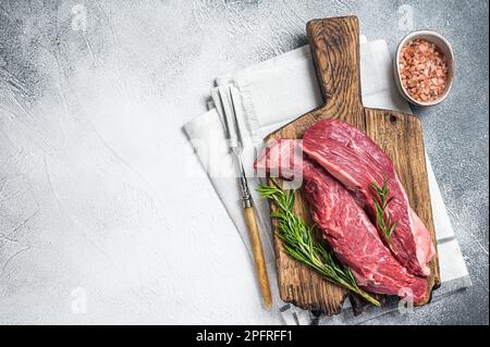 Fleischer wählen Bavette rohes Rindfleisch Steak oder Flankenklappe auf einem Holzbrett mit Kräutern. Weißer Hintergrund. Draufsicht. Speicherplatz kopieren. Stockfoto