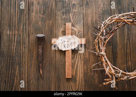 Er ist Risen. Jesus Krone Dornen und Nägel und Kreuz auf Holzhintergrund. Ostertag Stockfoto