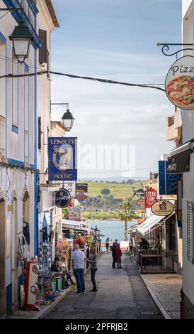 Eine enge Straße mit Bars und Souvernir-Geschäften in der Stadt Alvor, Algarve, Portugal Stockfoto