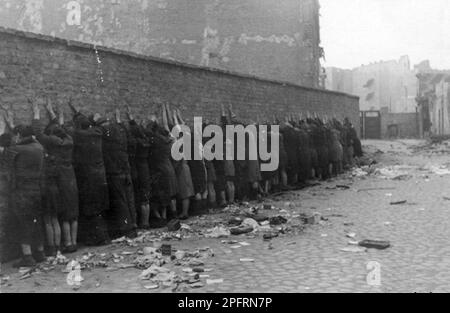 Im Januar 1943 kamen die nazis an, um die Juden des Warschauer Ghettos zu verhaften. Die Juden, die entschlossen waren, es zu bekämpfen, nahmen es mit selbstgemachten und primitiven Waffen auf die SS abgesehen. Die Verteidiger wurden hingerichtet oder deportiert, und das Ghetto-Gebiet wurde systematisch abgerissen. Dieses Ereignis ist bekannt als Ghetto-Aufstand. Dieses Bild zeigt Juden, die von der SS während der Unterdrückung des Warschauer Ghetto-Aufstands gefangen wurden, vor der Suche nach Waffen an einer Wand. Dieses Bild stammt aus der deutschen Fotoaufzeichnung des Ereignisses, bekannt als Stroop-Bericht. Stockfoto
