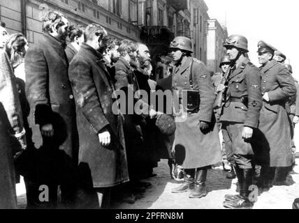 Im Januar 1943 kamen die nazis an, um die Juden des Warschauer Ghettos zu verhaften. Die Juden, die entschlossen waren, es zu bekämpfen, nahmen es mit selbstgemachten und primitiven Waffen auf die SS abgesehen. Die Verteidiger wurden hingerichtet oder deportiert, und das Ghetto-Gebiet wurde systematisch abgerissen. Dieses Ereignis ist bekannt als Ghetto-Aufstand. Dieses Bild zeigt deutsche Soldaten, die mit Rabbi Heschel Rappaport sprechen. Dieses Bild stammt aus der deutschen Fotoaufzeichnung des Ereignisses, bekannt als Stroop-Bericht. Stockfoto