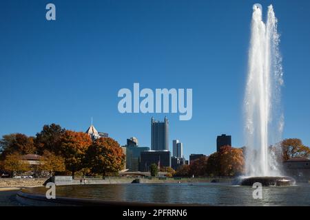 Blick über die Innenstadt von Pittsburgh mit dem Brunnen im Point State Park und fallsfarbenen Bäumen und klarem blauen Himmel. Stockfoto