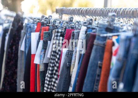 Mehrfarbige Herren- und Damenhosen auf einem Geländer am Eingang des Ladens. Alte Wohltätigkeitsmesse Stockfoto