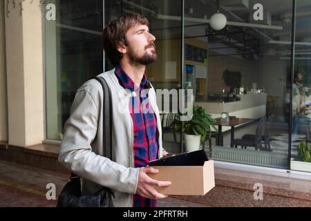 Büroangestellter mit einer Schachtel Sachen, lässt Arbeit. Der Geschäftsmann verlor aufgrund der Wirtschaftskrise seinen Job. Arbeitslosenkonzept Stockfoto