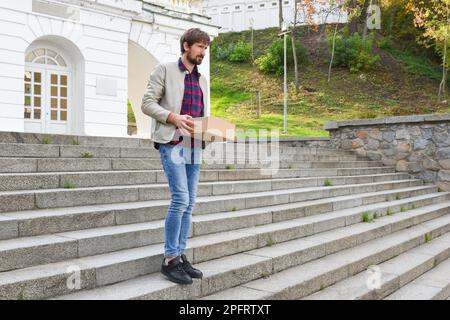 Büroangestellter mit einer Schachtel Sachen, lässt Arbeit. Der Geschäftsmann verlor aufgrund der Wirtschaftskrise seinen Job. Arbeitslosenkonzept Stockfoto