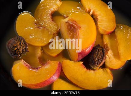 Saftige, reife Pfirsiche in eigenem Saft. Schließen. Auf schwarzem Hintergrund Stockfoto
