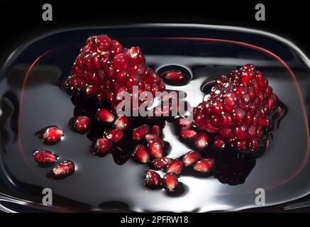 Saftige Granatapfelsamen im eigenen Saft. Nahaufnahme vor einem dunklen Hintergrund Stockfoto