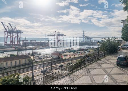 Lissabon, Portugal - 4. Dezember 2022: Containerterminal Liscont und Brücke 25 de Abril. Stockfoto