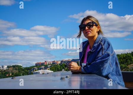 Eine Frau, die an einer Mauer gegen den Himmel steht Stockfoto