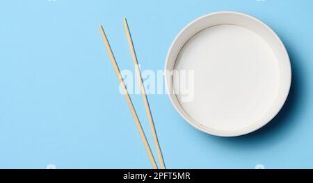 Öffnen Sie die leere Nudelschüssel mit einem Paar Holzstäbchen auf blauem Hintergrund, Draufsicht Stockfoto