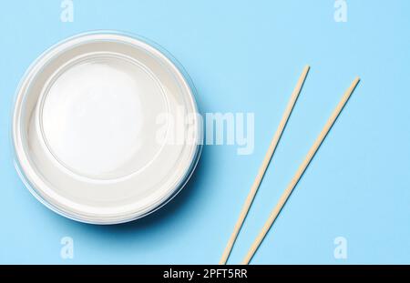 Öffnen Sie die leere Nudelschüssel mit einem Paar Holzstäbchen auf blauem Hintergrund, Draufsicht Stockfoto