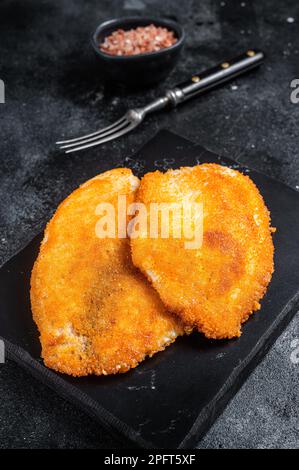 Gebratene panierte Tilapia-Filets auf einem Marmorbrett. Schwarzer Hintergrund. Draufsicht. Stockfoto