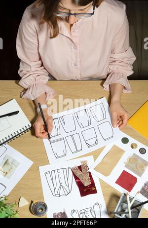 Modedesignerin zeichnet Skizzen von Kleidung auf Papier. Stockfoto