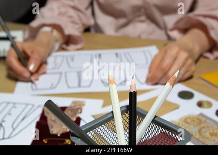 Modedesignerin zeichnet Skizzen von Kleidung auf Papier. Stockfoto