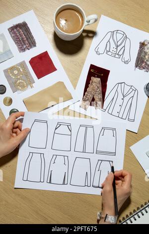 Modedesignerin zeichnet Skizzen von Kleidung auf Papier. Stockfoto