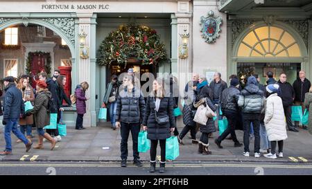 [MccLi0002147] die Leute tragen blaue Einkaufstaschen, wenn sie Fortnum & Mason heute Nachmittag verlassen, am letzten Shopping-Wochenende vor Weihnachten. Bild e Stockfoto