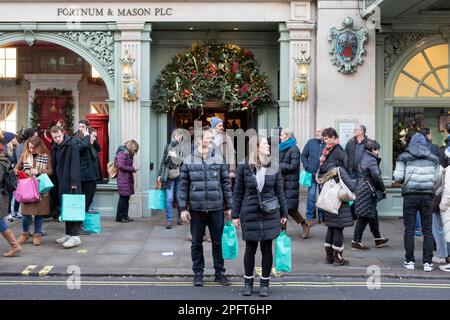 [MccLi0002147] die Leute tragen blaue Einkaufstaschen, wenn sie Fortnum & Mason heute Nachmittag verlassen, am letzten Shopping-Wochenende vor Weihnachten. Bild e Stockfoto