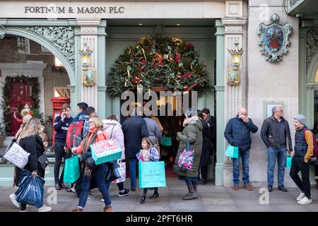 [MccLi0002147] die Leute tragen blaue Einkaufstaschen, wenn sie Fortnum & Mason heute Nachmittag verlassen, am letzten Shopping-Wochenende vor Weihnachten. Bild e Stockfoto