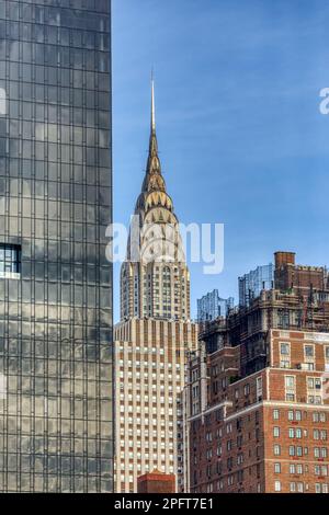 Der berühmte Turm des Chrysler Building, eingerahmt von schwarzem Glas der First Avenue aus dem Jahr 685, dem orangefarbenen Daily News Building und dem Windsor Tower von Tudor City. Stockfoto