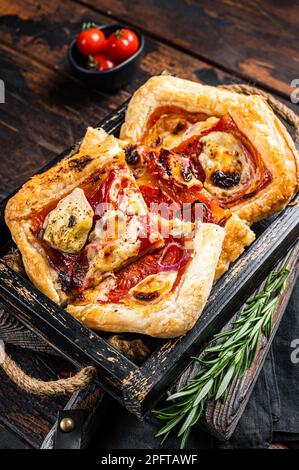 Blätterteig Tortenpizza mit Artischocke, Mozzarella, Tomaten und Käse in einem Holztablett. Holzhintergrund. Draufsicht. Stockfoto