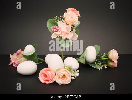 Pastellblumen mit weißen ostereiern auf dunklem Hintergrund Stockfoto