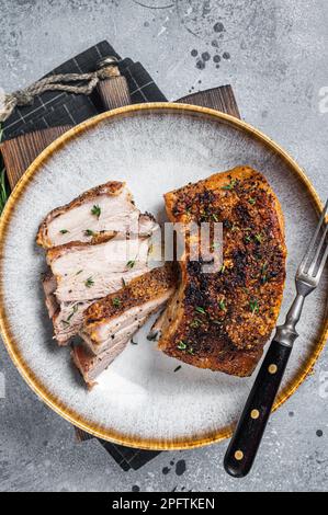 Philippinisch marinierter Schweinebauch mit Kruste auf einem Teller. Grauer Hintergrund. Draufsicht. Stockfoto