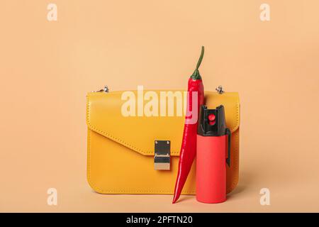 Beutel mit Spray und Chili-Pfeffer auf beigefarbenem Hintergrund Stockfoto