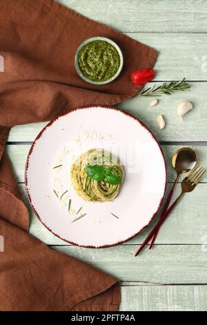 Teller mit schmackhafter Pesto-Pasta auf farbigem Holzhintergrund Stockfoto