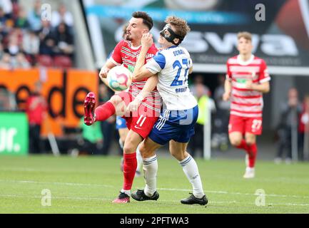 Deutschland. 18. März 2023. Augsburg, Deutschland. 18. März 2023. firo : 03/18/2023, Fußball, 1. Liga, 1. Bundesliga, Staffel 2022/2023, 25. Spieltag FC Augsburg - FC Schalke 04 1: 1, Mergim Berisha, FC Augsburg, FCA, Augsburg, Cedric Brunner, FC Schalke 04, S04, Schalke, ganze Figur, Duels, Kredit: dpa/Alamy Live News Kredit: dpa Picture Alliance/Alamy Live News Stockfoto