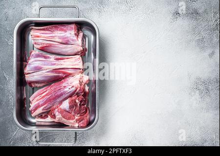 Frisches rohes Lamm legt Fleisch in eine Stahlschale. Weißer Hintergrund. Draufsicht. Speicherplatz kopieren. Stockfoto