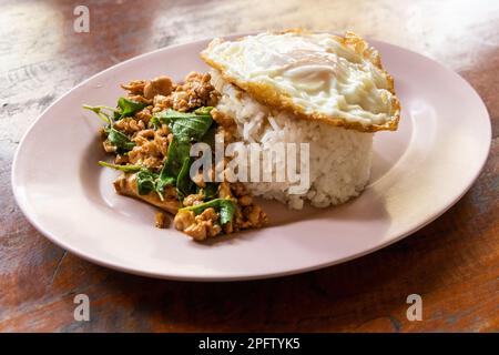 Serviert wird Prad Ka Pao, beliebtes thailändisches Essen aus gebratenem Schweinehackfleisch mit Basilikum und Spiegelei mit Reis Stockfoto