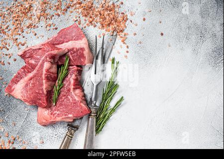 Silberseidenfilet-Rindfleisch geschnitten, rohes Fleisch auf dem Metzgertisch mit Kräutern. Weißer Hintergrund. Draufsicht. Speicherplatz kopieren. Stockfoto