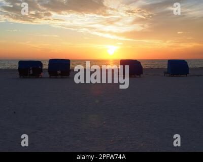 Blaue Cabanas am Strand bei Sonnenuntergang Stockfoto
