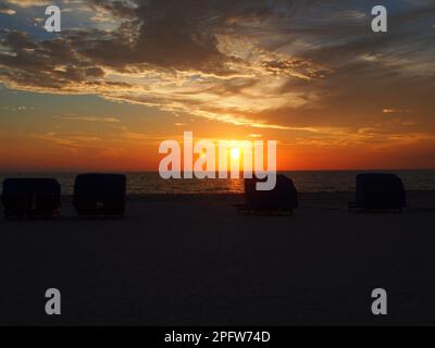 Blaue Cabanas am Strand bei Sonnenuntergang Stockfoto