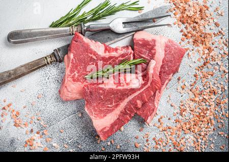 Silberseidenfilet-Rindfleisch geschnitten, rohes Fleisch auf dem Metzgertisch mit Kräutern. Weißer Hintergrund. Draufsicht. Stockfoto