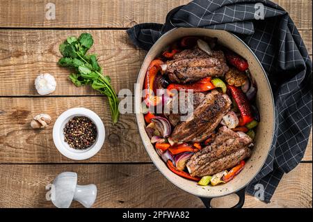 Geröstete, langsam gekochte Lammschäfte mit Gemüse und Kräutern. Holzhintergrund. Draufsicht. Stockfoto