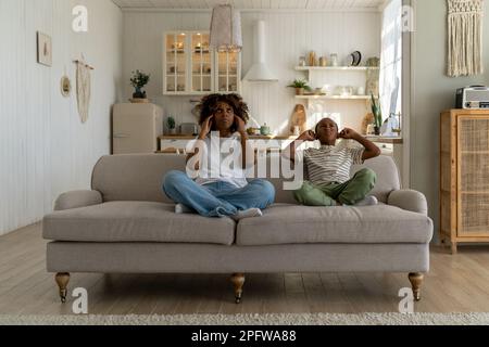 Verärgerte gestresste Familie mutter und Kind sitzen auf dem Sofa und waren sehr genervt vom Nachbarlärm Stockfoto