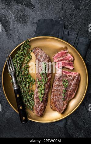 BBQ gegrilltes Bavette Bavet Rindfleisch Steak mit Kräutern auf einem Teller. Schwarzer Hintergrund. Draufsicht. Stockfoto