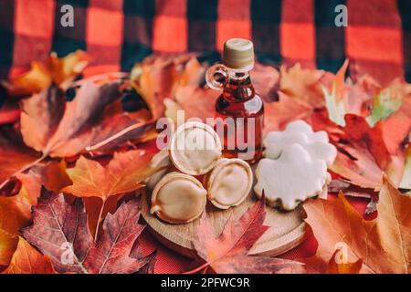 Ahornsirupbutter und Toffee mit Keksen in Blattform auf traditionellem Karottentisch in Quebec mit roten Herbstblättern. Kleine Geschenkflasche. Traditionell Stockfoto