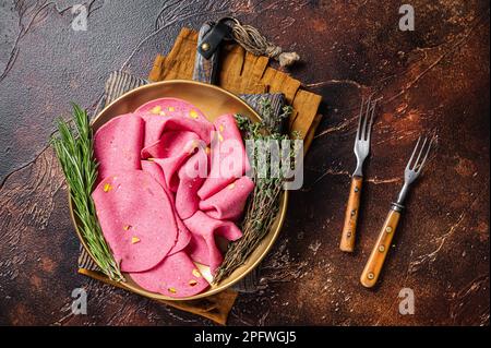 Salami-Scheiben mit Pistaziennüssen in Stahlplatte mit Thymian und Rosmarin. Dunkler Hintergrund. Draufsicht. Stockfoto