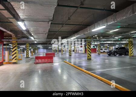 Selektiver Fokus auf Tiefgaragenparkplätze in einem Einkaufszentrum. Parkbeschränkungen. Mit einem Platz zum Kopieren. Navigation auf dem Parkplatz. Kostenloser Parkplatz. Hochwertiges Foto Stockfoto