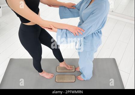 Weiße Frau steht auf Sadhu-Brettern mit Therapeuten-Unterstützung. Stockfoto