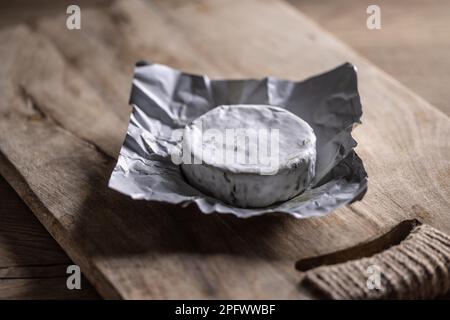 Geöffnete Packung Camembert-Käse auf einem Holzbrett. Stockfoto